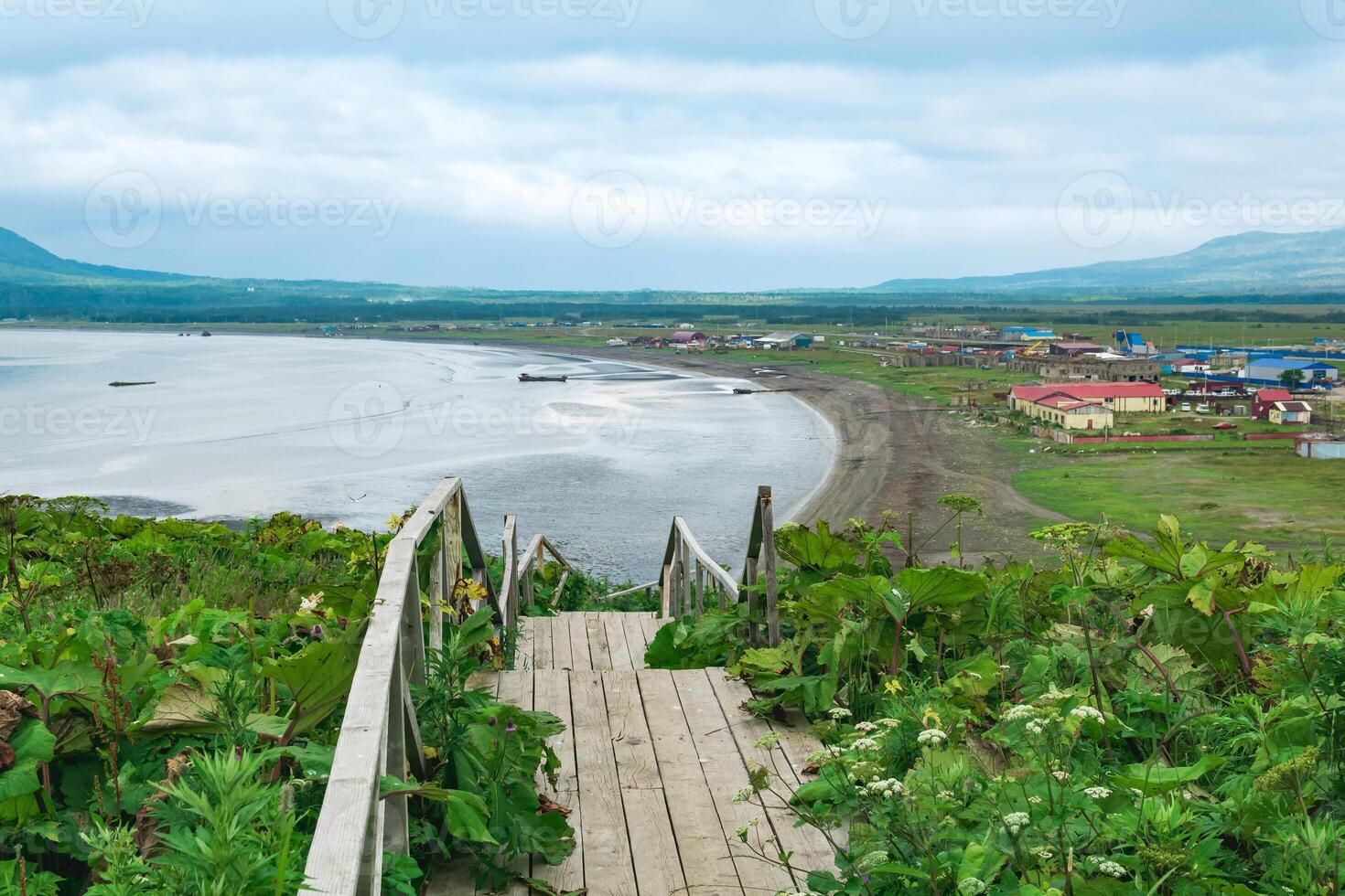 visie van de baai van Joezjno-Koerilsk Aan de eiland van kunashir van een hoog kaap, in de voorgrond een houten trottoir met een ladder foto