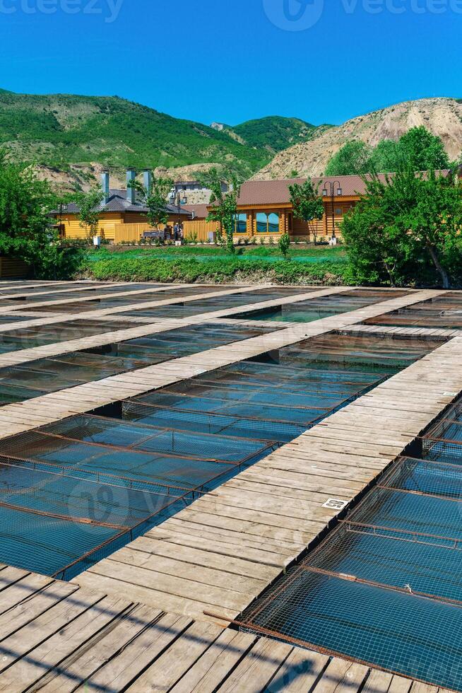 vis boerderij in een berg vallei met aquacultuur kooien en houten gebouwen foto