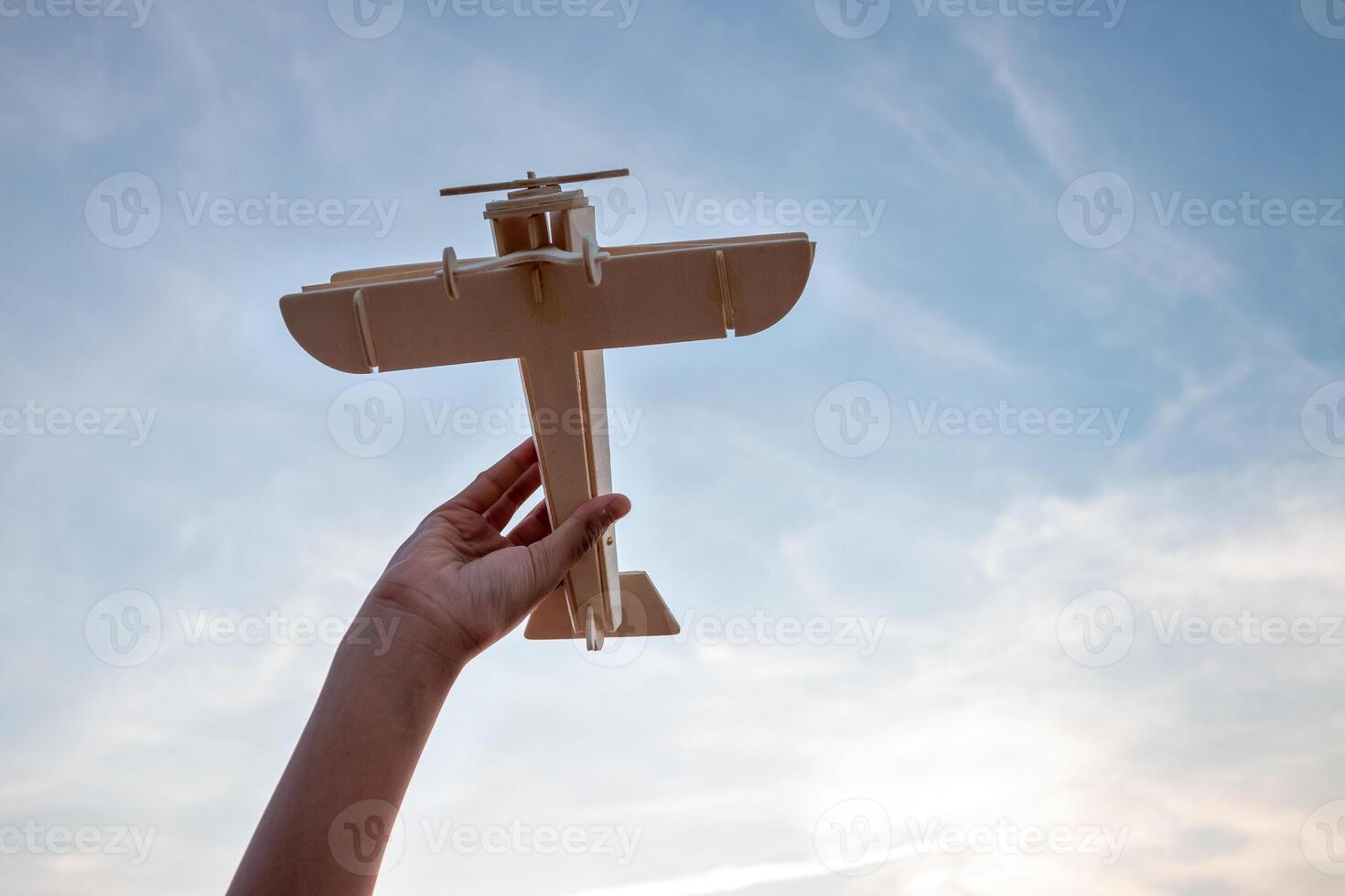 kind Holding een houten vliegtuig model- hoog in de lucht foto