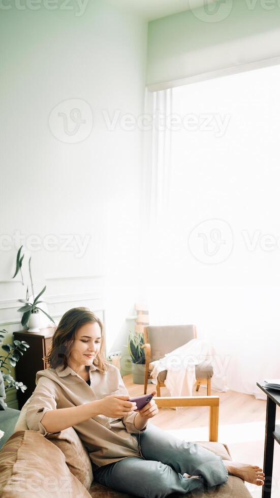 blij multitasking. glimlachen jong vrouw moeiteloos types Aan haar smartphone, bezighoudt in een spel, en geniet aan het kijken een video presentatie van de veelzijdigheid van modern digitaal interacties foto