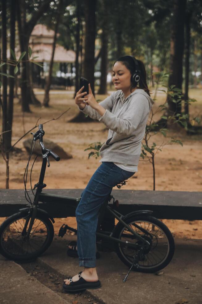 gelukkig Aziatisch jong vrouw wandelen en rijden fiets in park, straat stad haar glimlachen gebruik makend van fiets van vervoer, eco vriendelijk, mensen levensstijl concept. foto