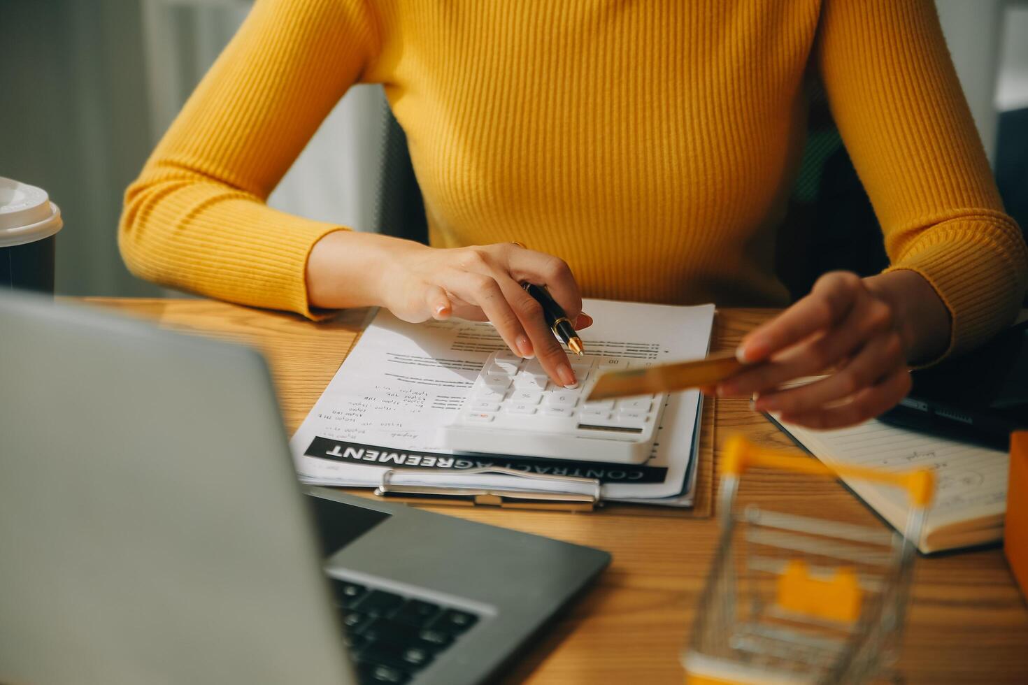 jong vrouw Holding een smartphone, tablet tonen betaling succes en credit kaart met geel pakket doos net zo online boodschappen doen concept in kantoor foto