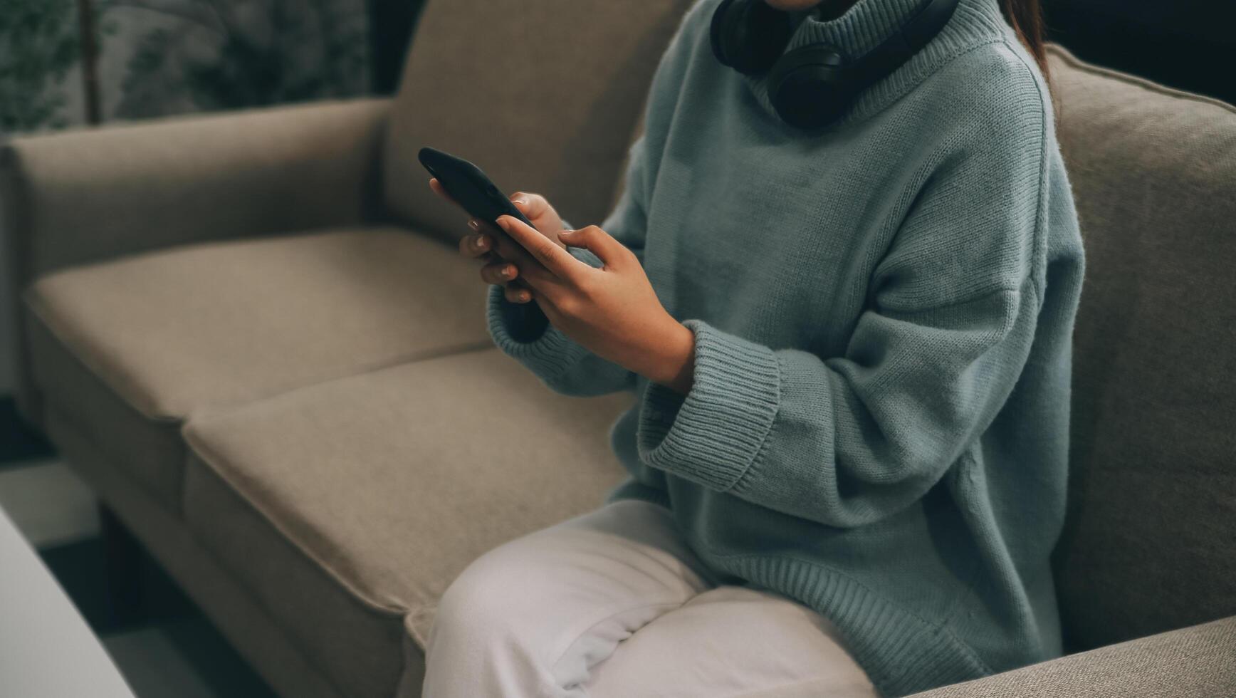 gelukkig mooi millennial Indisch meisje ontspannende Bij huis, resting in fauteuil, typen Aan smartphone, gebruik makend van online app, software, boodschappen doen Aan internetten, maken video telefoongesprek. mobiel telefoon communicatie foto