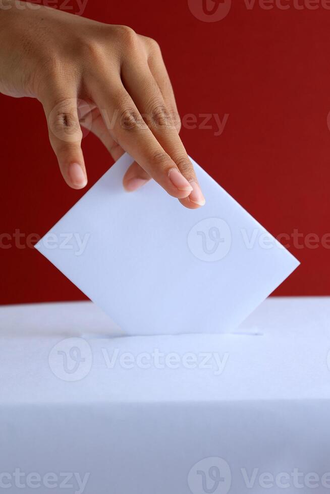 vrouw kiezer zetten stemmen kaart naar stemming doos met rood achtergrond foto