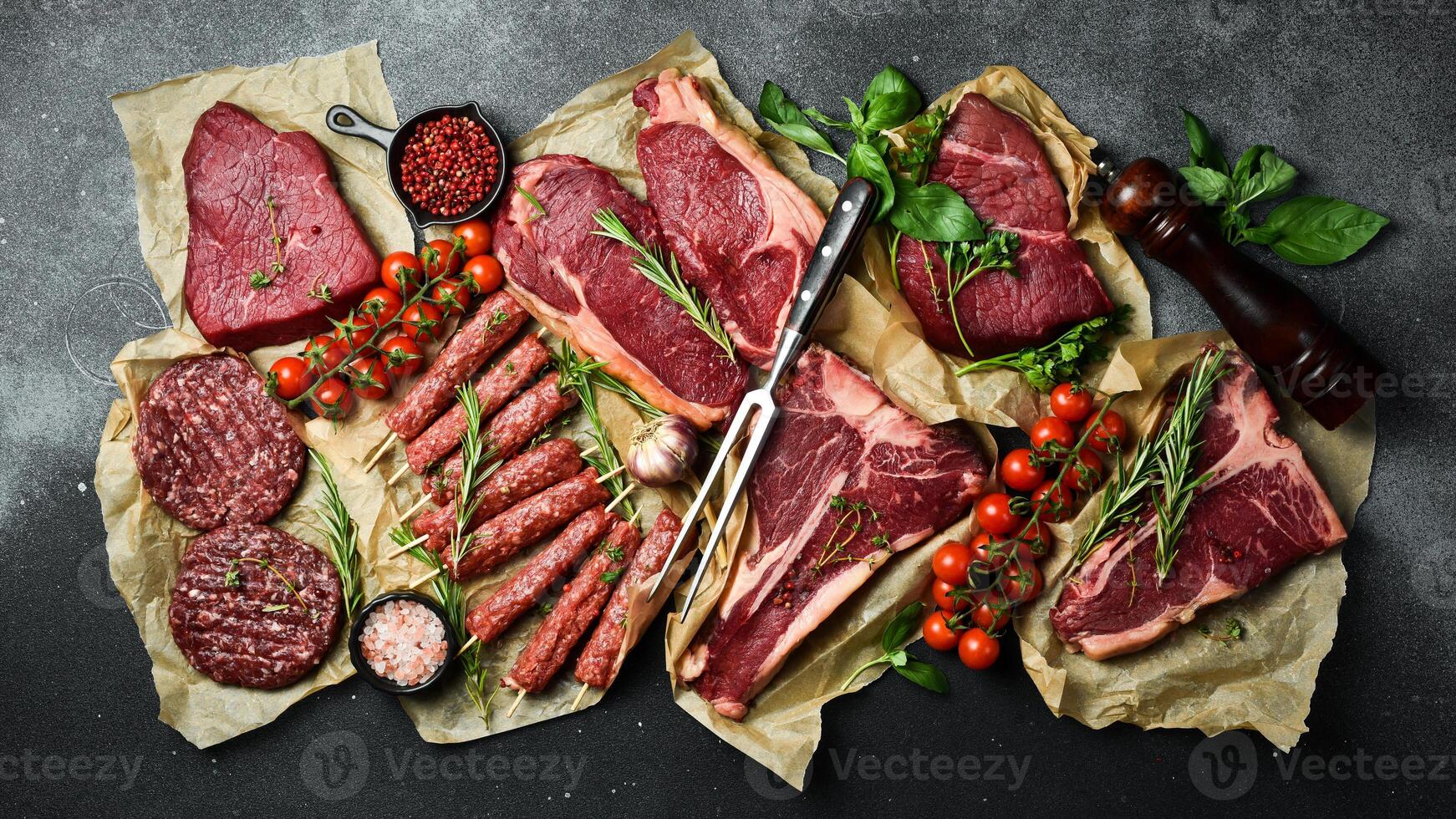 een reeks van sappig rauw steaks, kebab, schnitzels en vlees met specerijen en kruiden. Aan een zwart steen achtergrond. top visie. foto