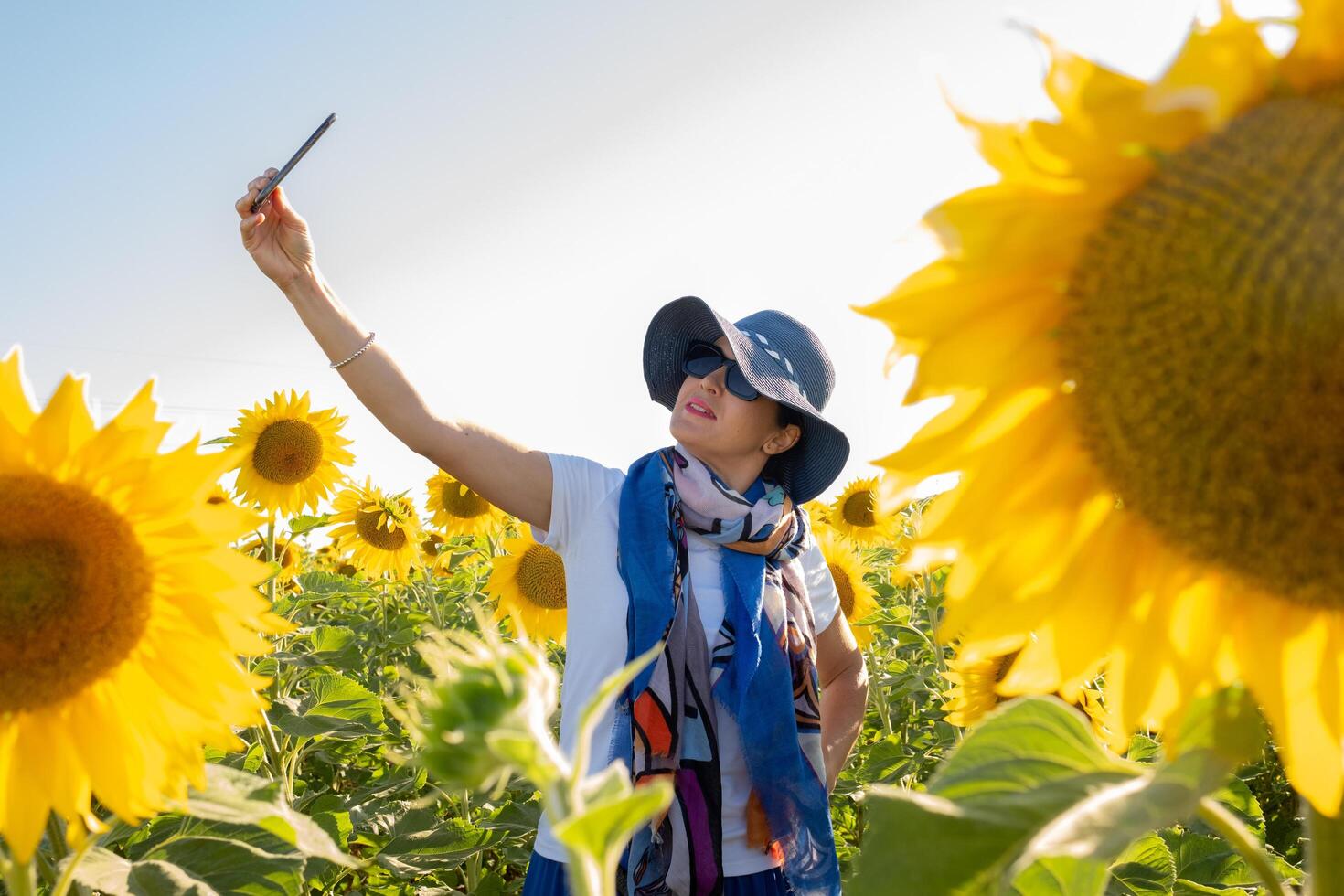 vrouw in hoed maken een selfie in een veld- van zonnebloemen foto