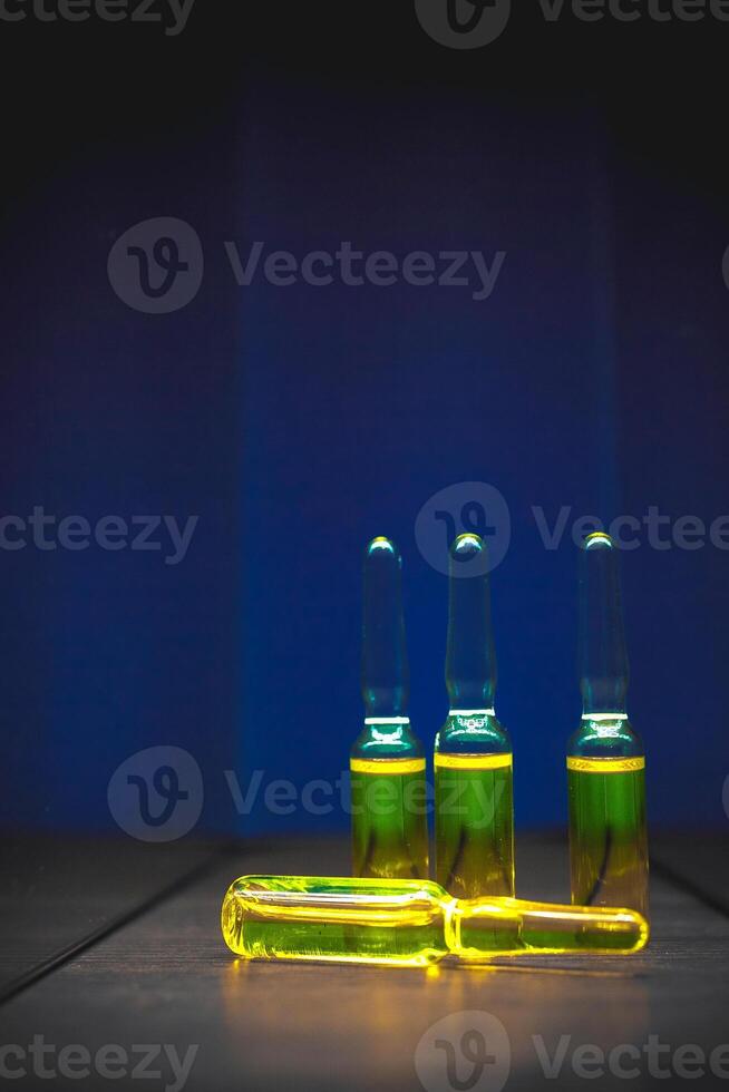 geel verdovend drugs, Chemicaliën, vitamines in ampullen Aan een blauw achtergrond. artistiek donker filter. laag sleutel foto