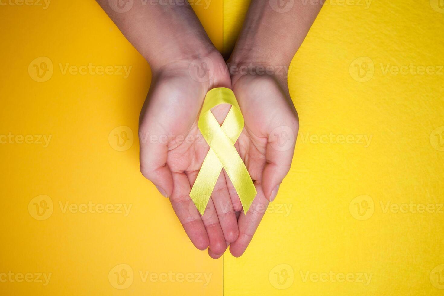 goud lint voor kinderen net zo een symbool van kinderjaren kanker bewustzijn. geel lint Aan hand- foto