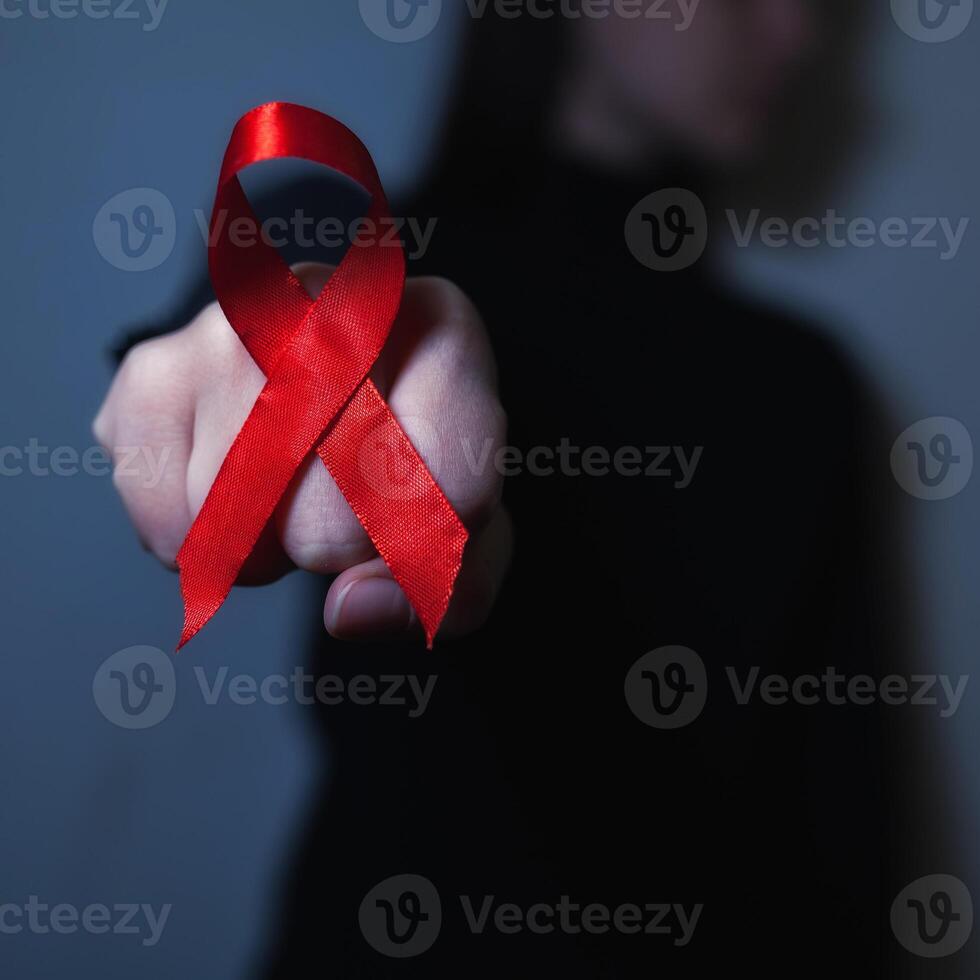 gezondheidszorg en geneeskunde concept. AIDS bewustzijn. rood AIDS bewustzijn lint Aan zwart achtergrond vuist gevecht. copyspace voor uw individu tekst. foto