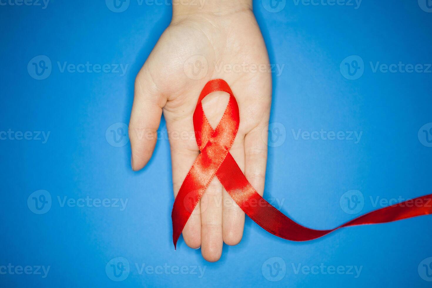 gezondheidszorg en geneeskunde concept. AIDS bewustzijn. rood AIDS bewustzijn lint Aan blauw achtergrond van bovenstaande. copyspace voor uw individu tekst. foto