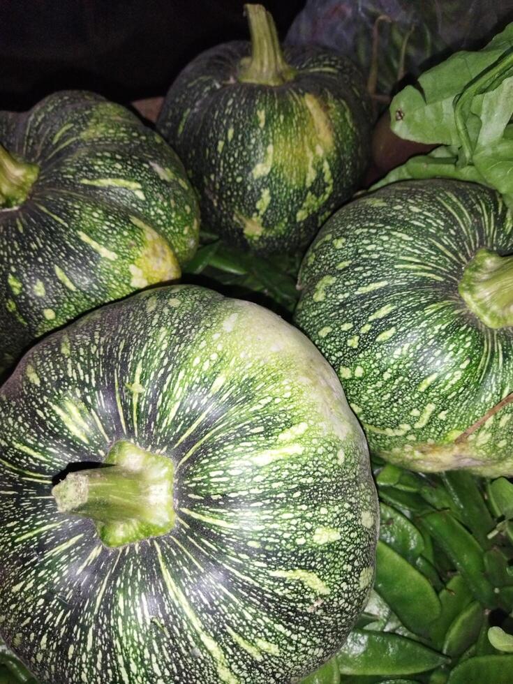 een bundel van groen en zwart squash zittend Aan top van bladeren foto