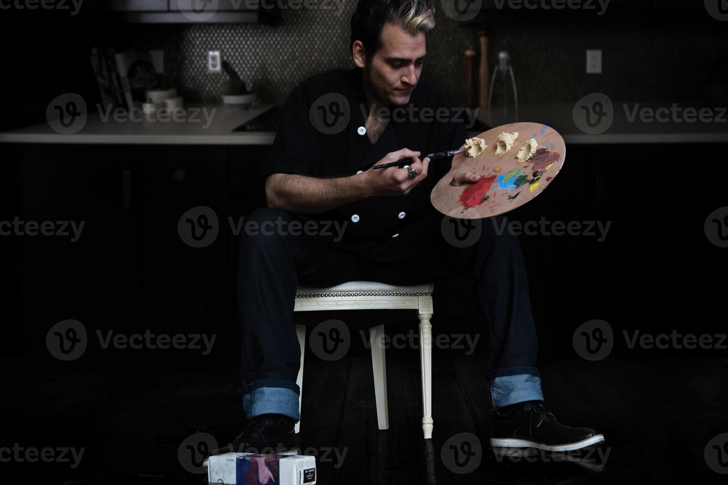 man in een keuken met een verfpalet met kleuren en hummuspasta foto