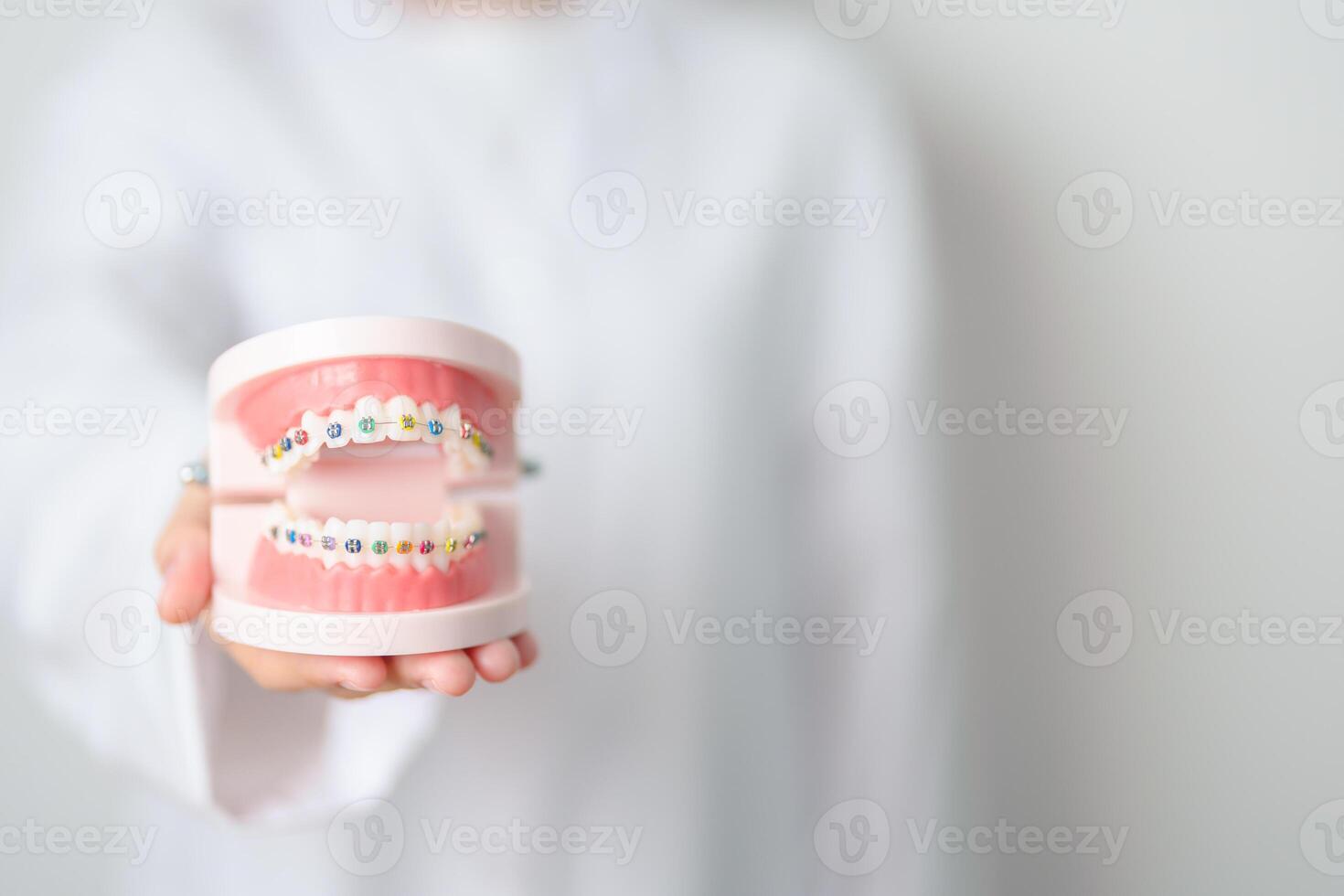 tandarts met orthodontisch tand model- en haakje of beugel. schoon en schrapen uit tandsteen. mei orthodontisch Gezondheid dag, maart mondeling Gezondheid, tandarts dag, false tanden. kiespijn en kinderen tandheelkundig Gezondheid foto