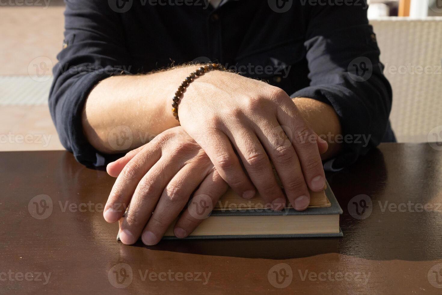 man's handen leugens Aan een oud boek, bruin houten tafel. hoog kwaliteit foto