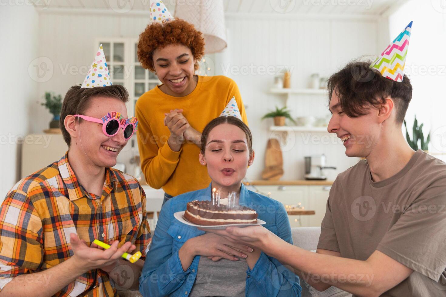 maken een wens. vrouw vervelend partij pet blazen uit brandend kaarsen Aan verjaardag taart. gelukkig verjaardag feest. groep van vrienden wensen meisje gelukkig verjaardag. mensen vieren verjaardag met partij Bij huis foto