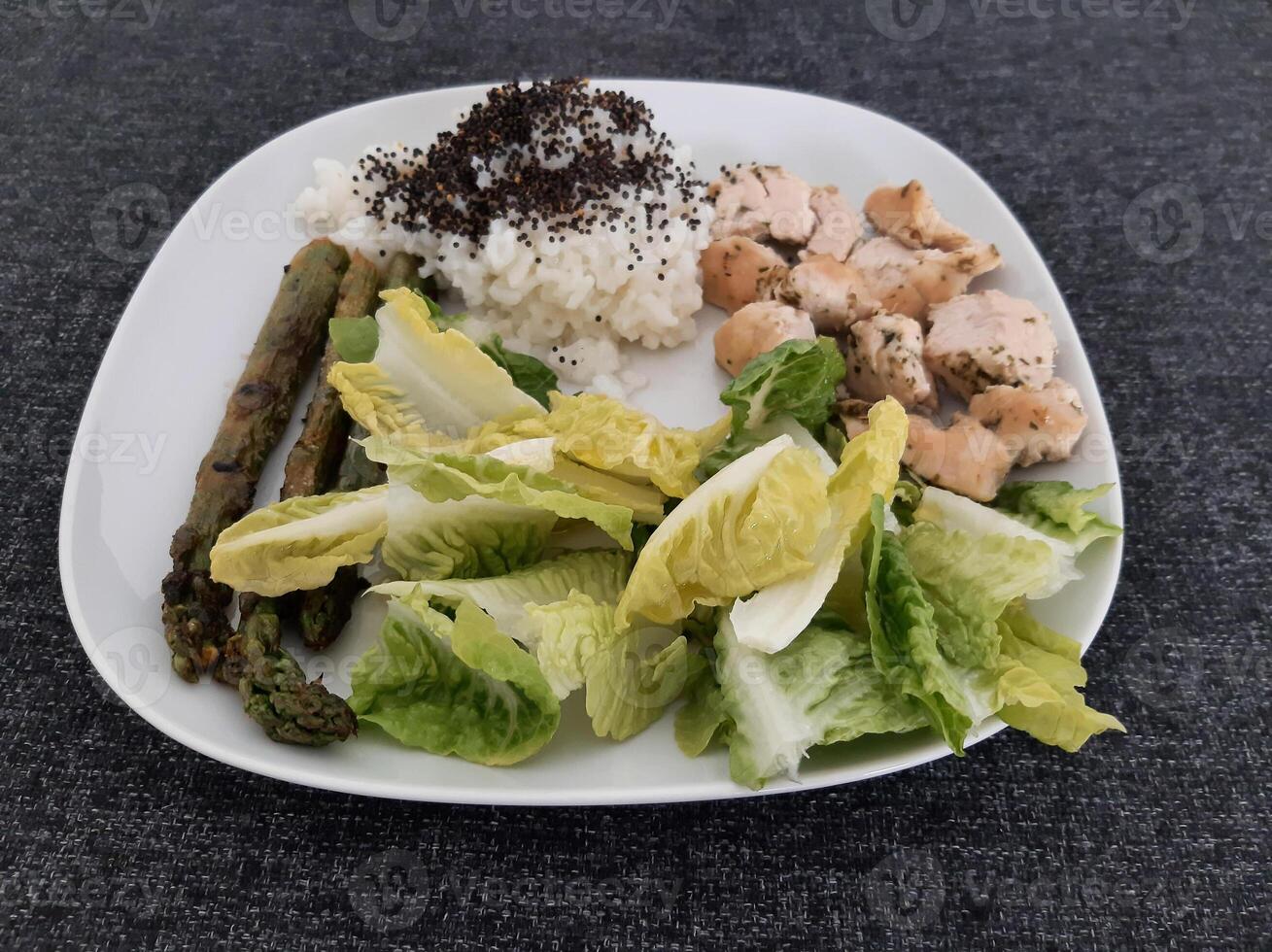 eigengemaakt gegrild kip met rijst- en gegrild asperges, geserveerd Aan een wit bord. brocolli zaden Aan top van de rijst- foto