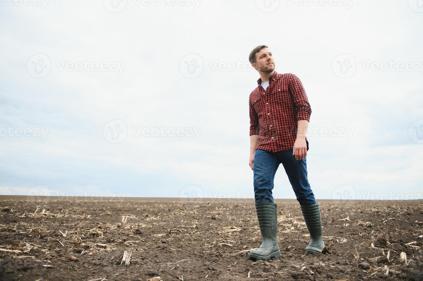 boer staand in een geploegd veld. landbouw, Bijsnijden concept. foto