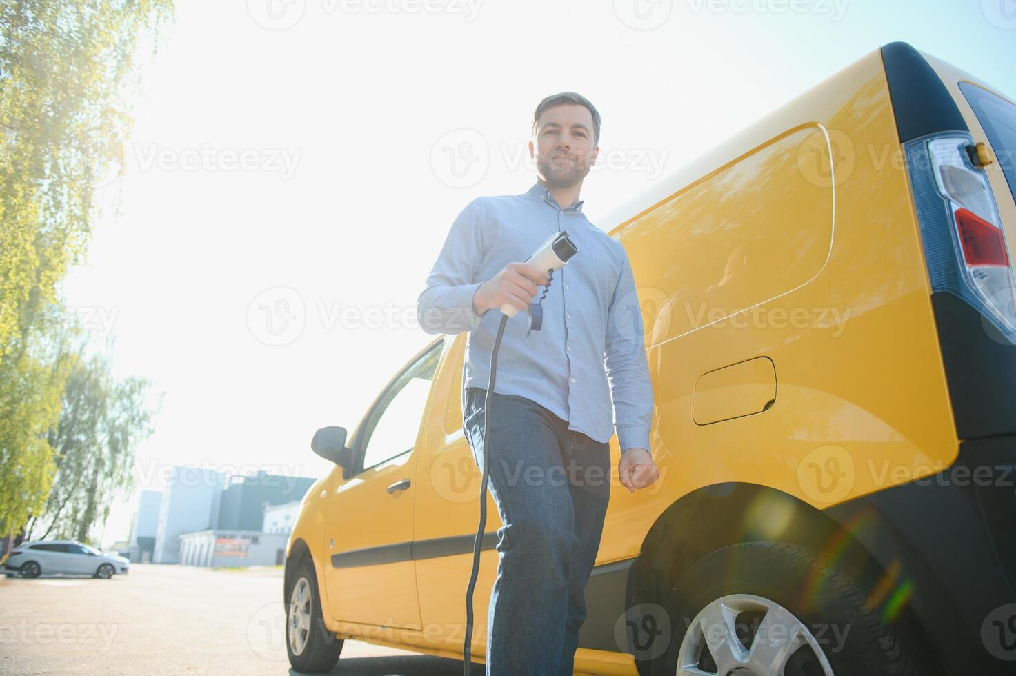 Mens opladen elektrisch auto door de huis foto