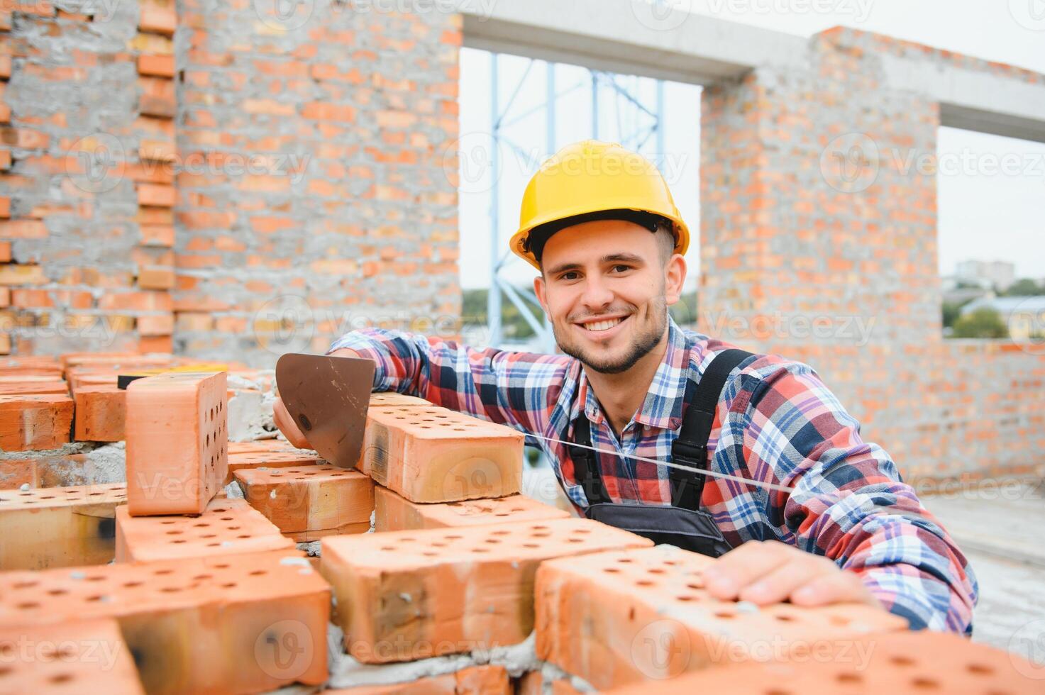 geel gekleurde moeilijk hoed. jong Mens werken in uniform Bij bouw Bij dag. foto