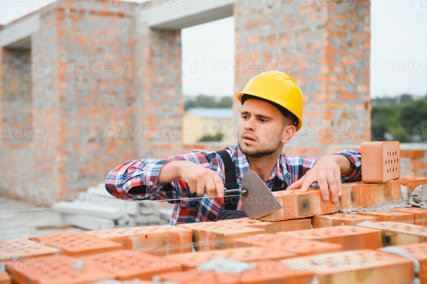 geel gekleurde moeilijk hoed. jong Mens werken in uniform Bij bouw Bij dag. foto
