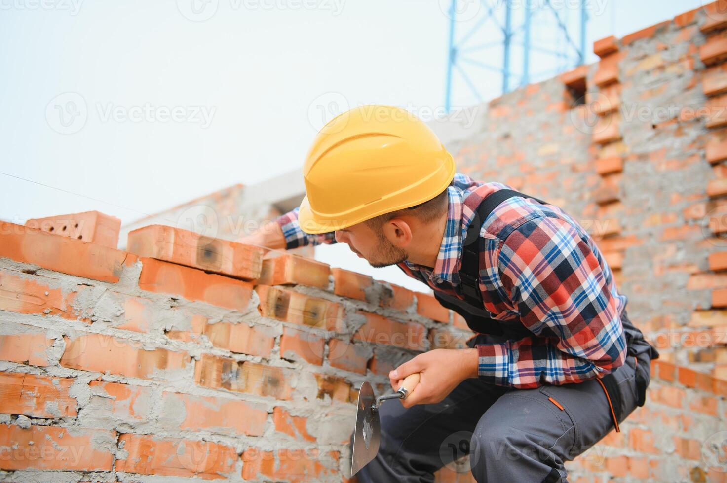 geel gekleurde moeilijk hoed. jong Mens werken in uniform Bij bouw Bij dag. foto