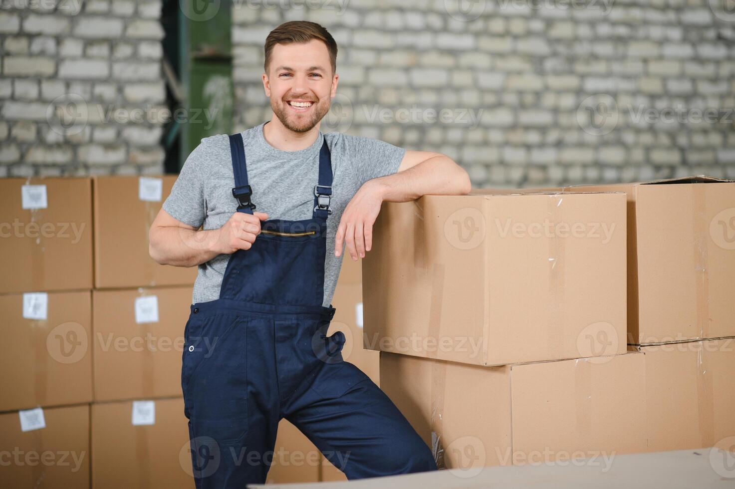 portret van gelukkig mannetje arbeider in magazijn staand tussen planken. foto