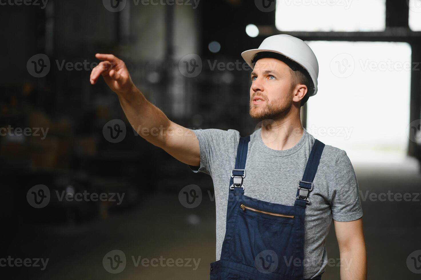 glimlachen en gelukkig medewerker. industrieel arbeider binnenshuis in fabriek. jong technicus met wit moeilijk hoed. foto