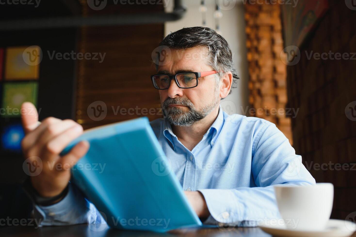 volwassen knap Mens lezing een boek in een cafe foto