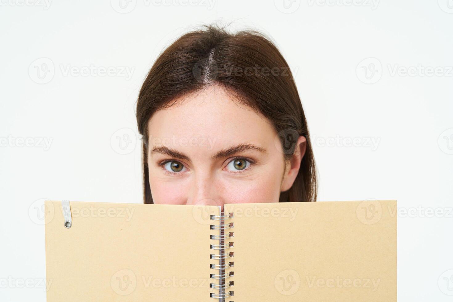 jong vrouw houdt notitieboekje dagelijks ontwerper De volgende naar haar gezicht, schrijven naar beneden huiswerk, maken notities, op zoek attent, staand over- wit achtergrond foto