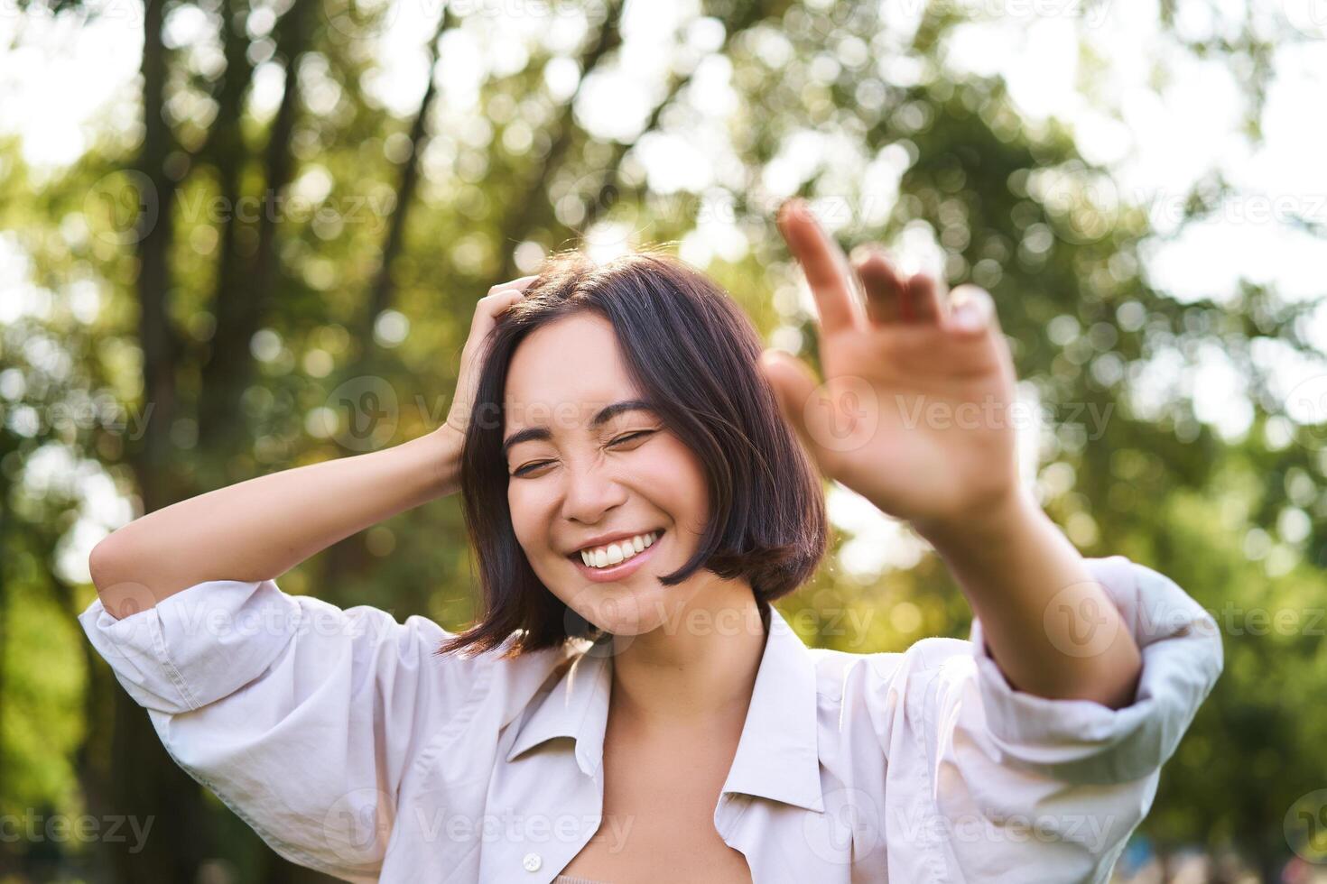 mensen en emoties concept. gelukkig Aziatisch vrouw lachend en lachend, poseren Aan zomer dag in park foto