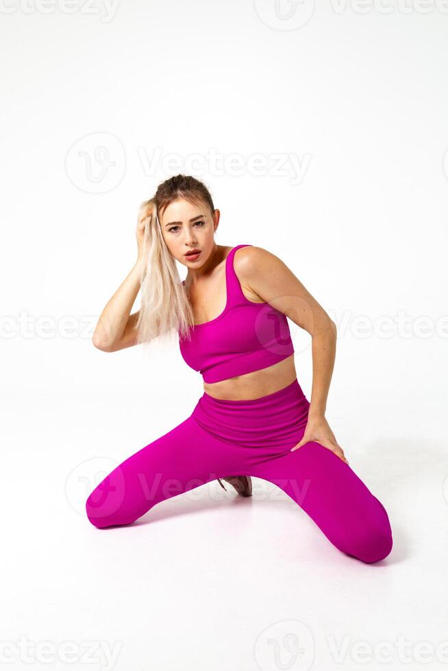vrouw in levendig roze sport- kleding beide knieën Aan verdieping en hand- in haren foto