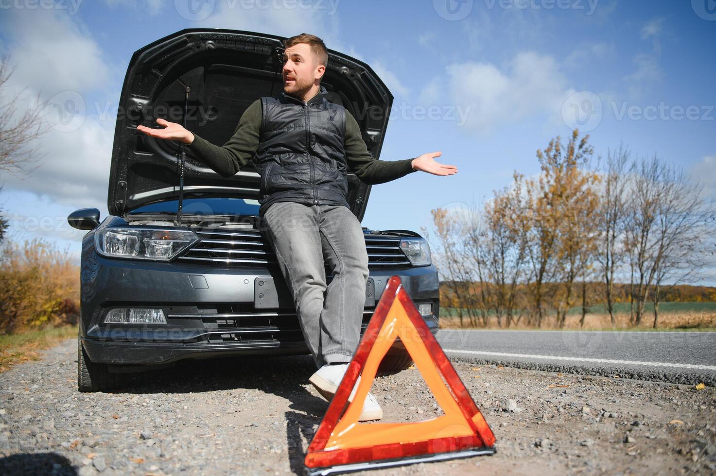 een jong Mens met een zwart auto dat kapot gegaan naar beneden Aan de weg, kopiëren ruimte. foto