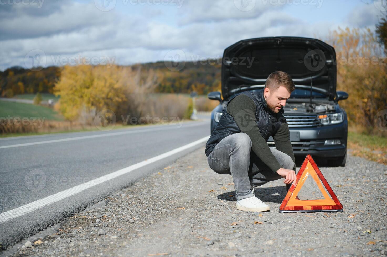 een jong Mens met een zwart auto dat kapot gegaan naar beneden Aan de weg, kopiëren ruimte. foto