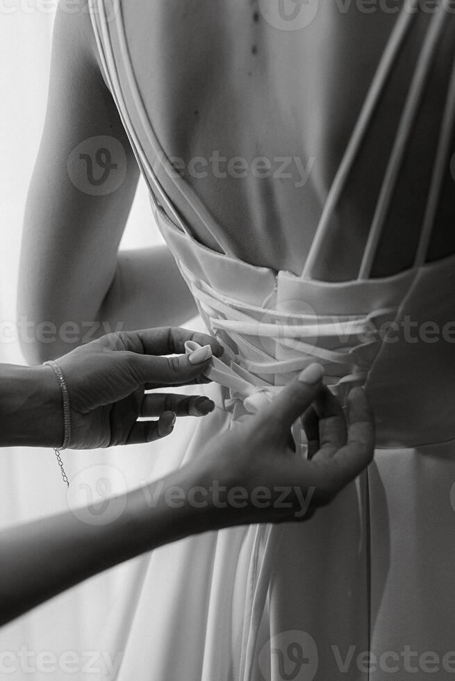 voorbereidende werkzaamheden voor de bruid met de dressing van de bruiloft jurk foto