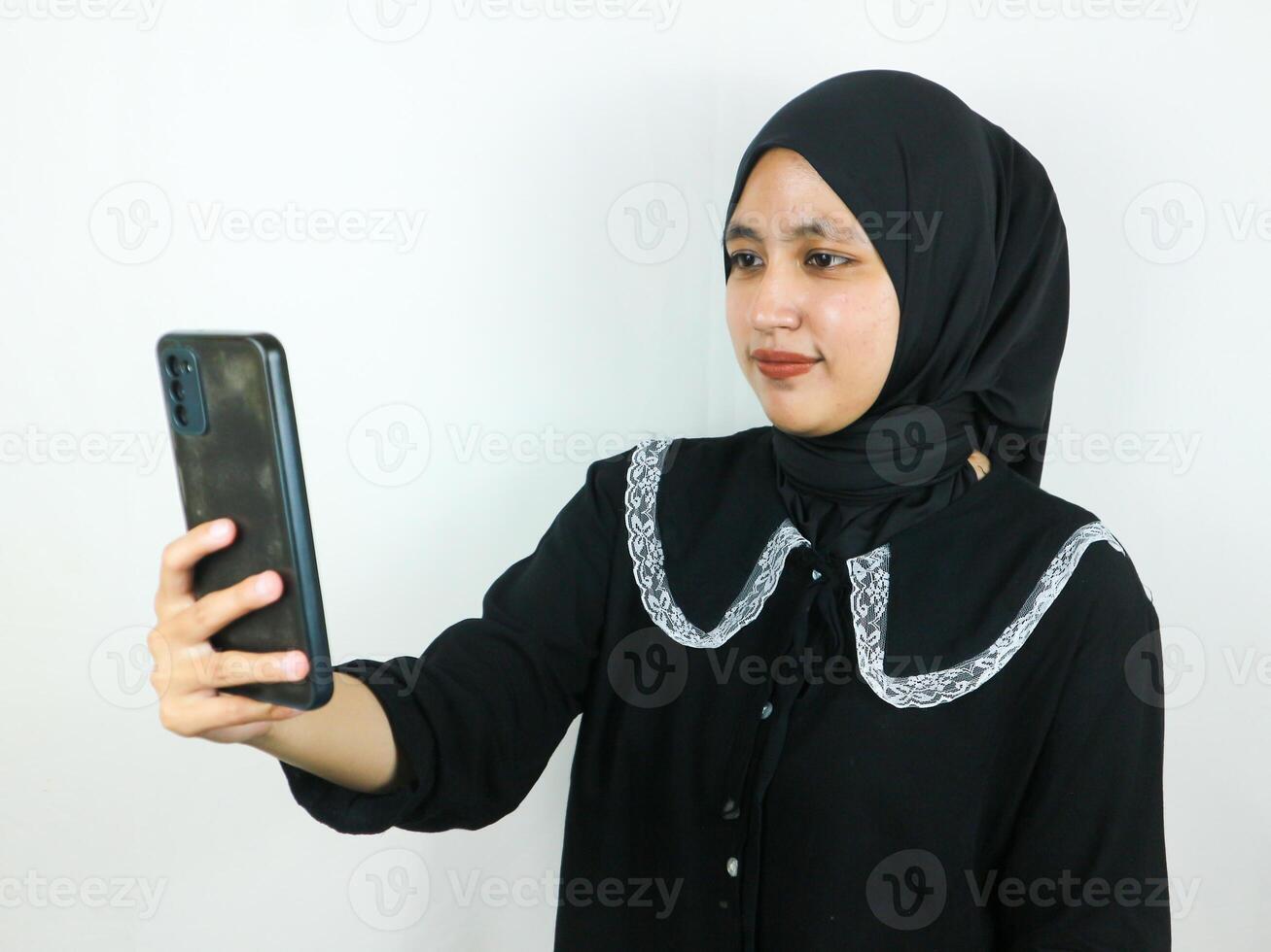 mooi jong Aziatisch vrouw vervelend hijab glimlachen en selfie nemen afbeeldingen door haar mobiel telefoon foto
