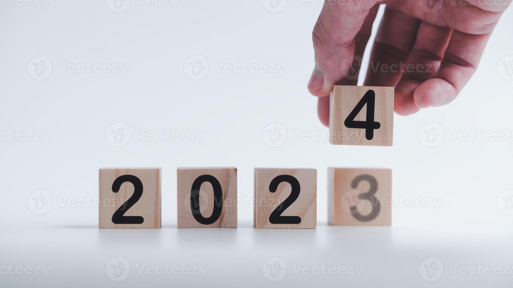 hand- Holding houten kubussen met de tekst 2023 2024 over- achtergrond naar verandering of vertaald van 2023 naar 2024. nieuw bedrijf doel strategie concept.2024 doel planning bedrijf concept foto