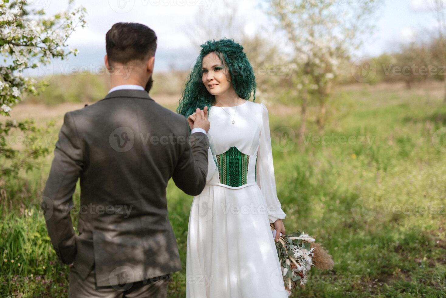 een gebaard bruidegom en een meisje met groen haar- dans en ronddraaien foto
