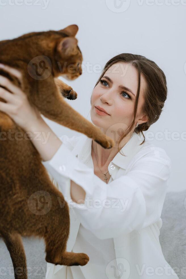 jong meisje in een wit kamer spelen met een kat foto