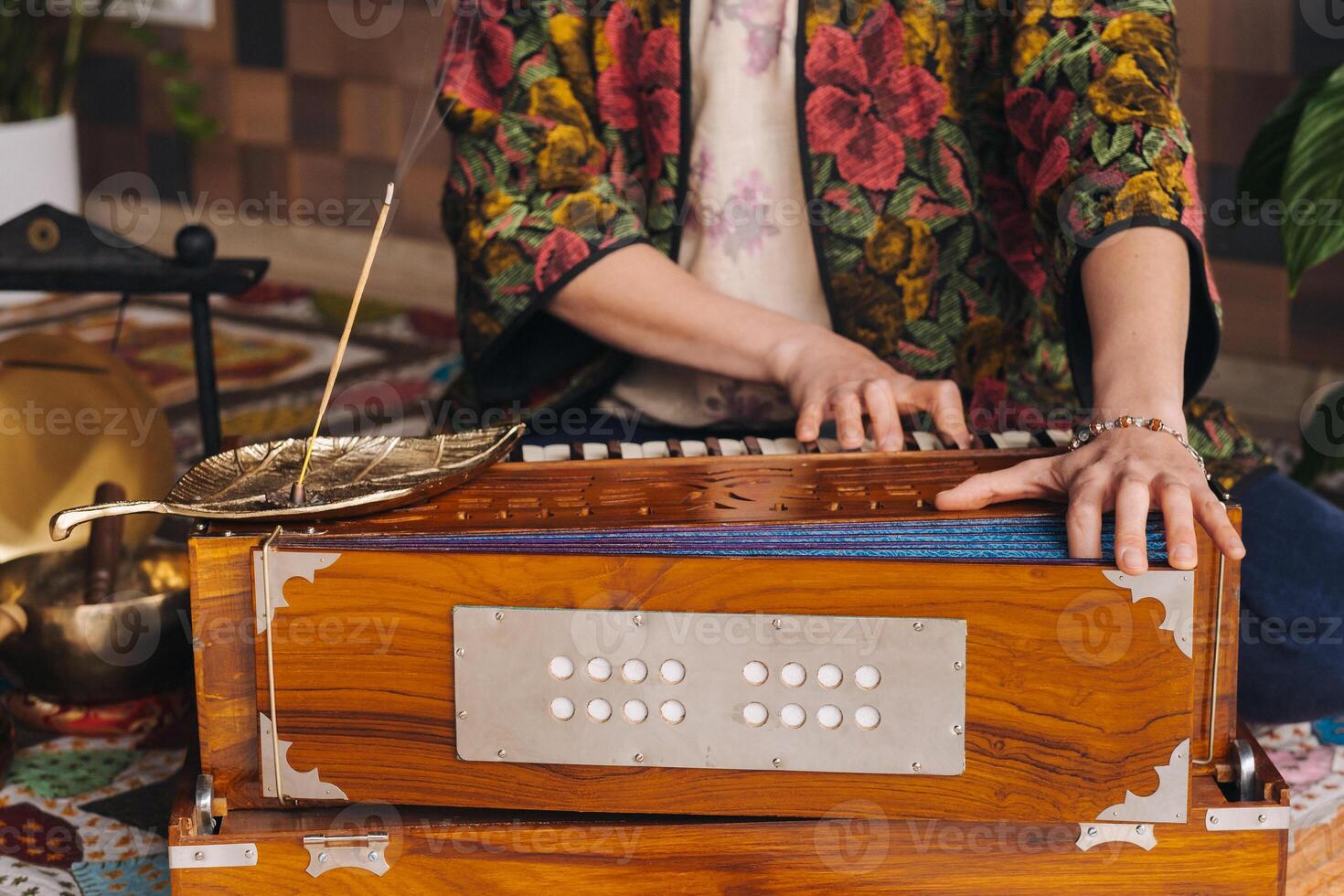 handen van een vrouw zittend Aan de verdieping en spelen de harmonium gedurende de praktijk van kundalini yoga foto