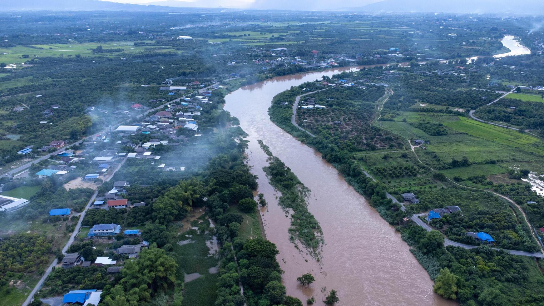 antenne visie van de ping rivier- aan de overkant rijst- velden en landelijk dorpen gedurende zonsondergang. keer bekeken van Chiang mai dorpen en de ping rivier- van een drone. foto