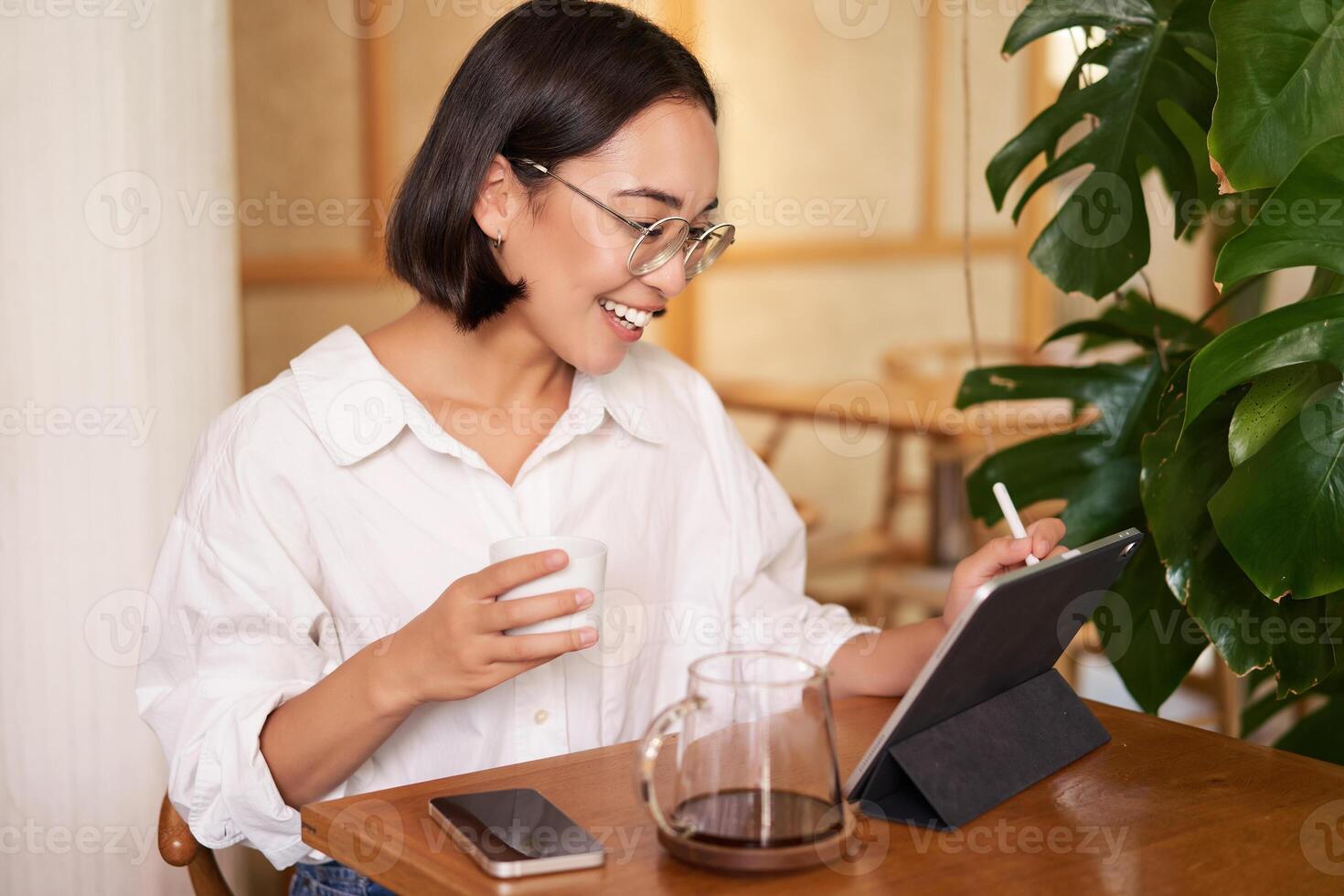 jong artiest tekening Aan digitaal tablet, gebruik makend van grafisch pen, drinken koffie in cafe en vangen iets foto