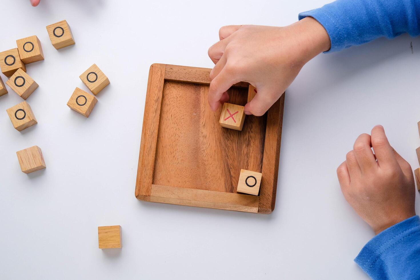 weinig broers en zussen spelen houten bord spel boter kaas en eieren Aan tafel in leven kamer. familie uitgeven tijd samen Aan weekend. foto