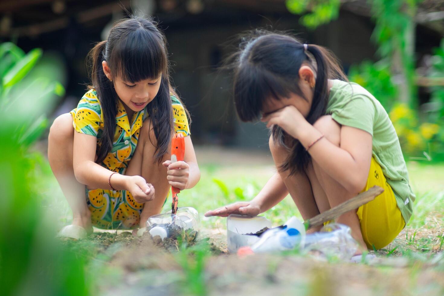 weinig meisje aanplant planten in potten van gerecycled water flessen in de achtertuin. recycle water fles pot, tuinieren activiteiten voor kinderen. recycling van plastic verspilling foto