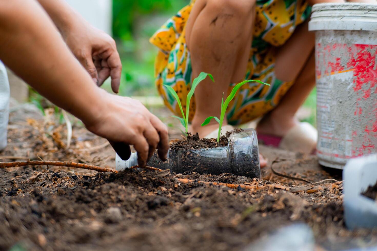 weinig meisje en mam toenemen planten in potten van gerecycled water flessen in de achtertuin. recycle water fles pot, tuinieren activiteiten voor kinderen. recycling van plastic verspilling foto