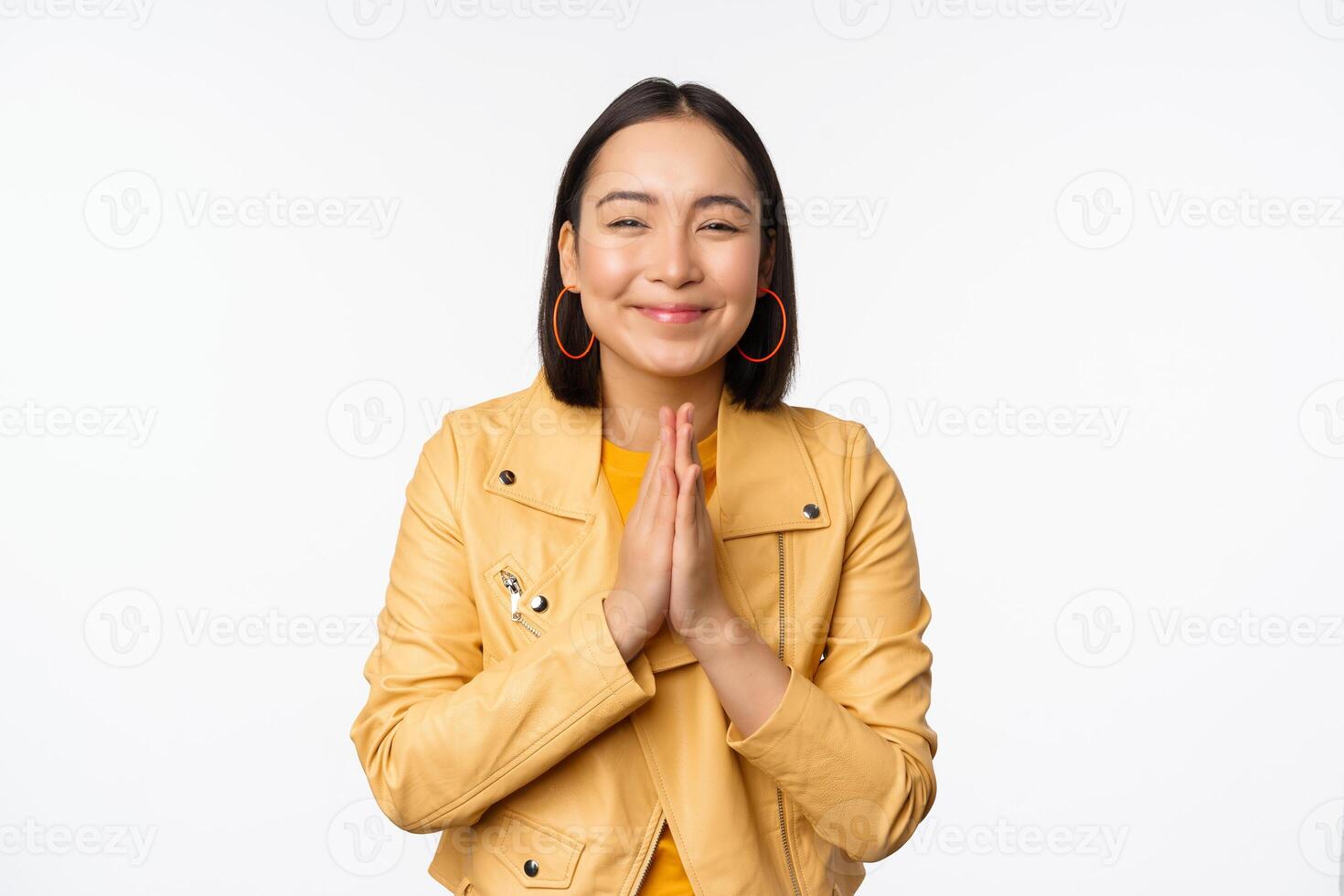 gelukkig Koreaans vrouw, op zoek hoopvol, vragen voor helpen gunst, bedelen, staand met namaste gebaar en lachend, staand over- wit achtergrond foto