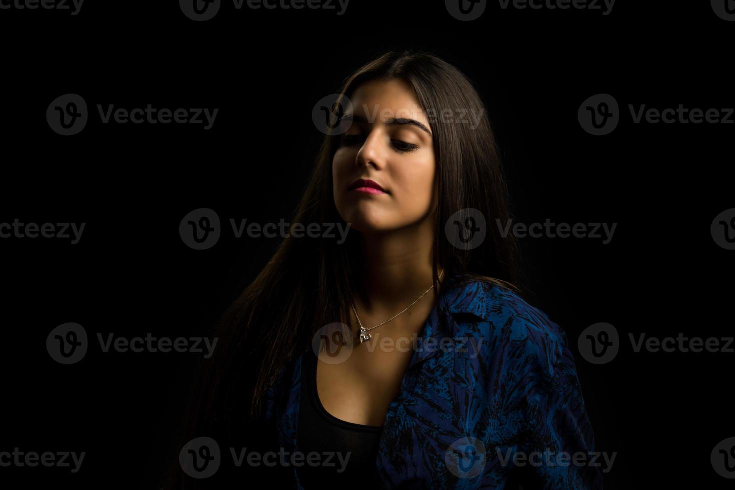 jonge brunette meisje met lang steil haar poseren, zwarte achtergrond foto