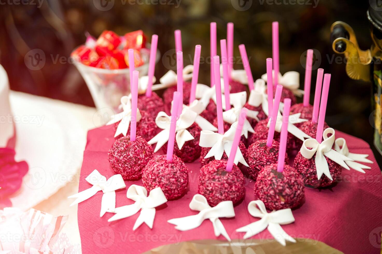 smakelijk taart knalt Aan roze stokjes versierd met wit bogen Aan de tafel. bruiloft buffet met heerlijk helder taart knalt Aan bordeaux servet. detailopname foto