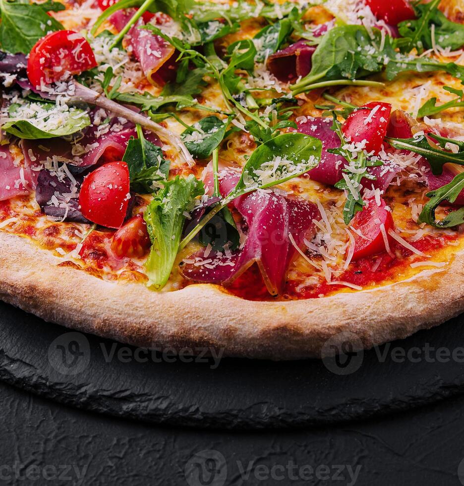 Italiaans pizza met prosciutto, rucola en kers tomaten foto