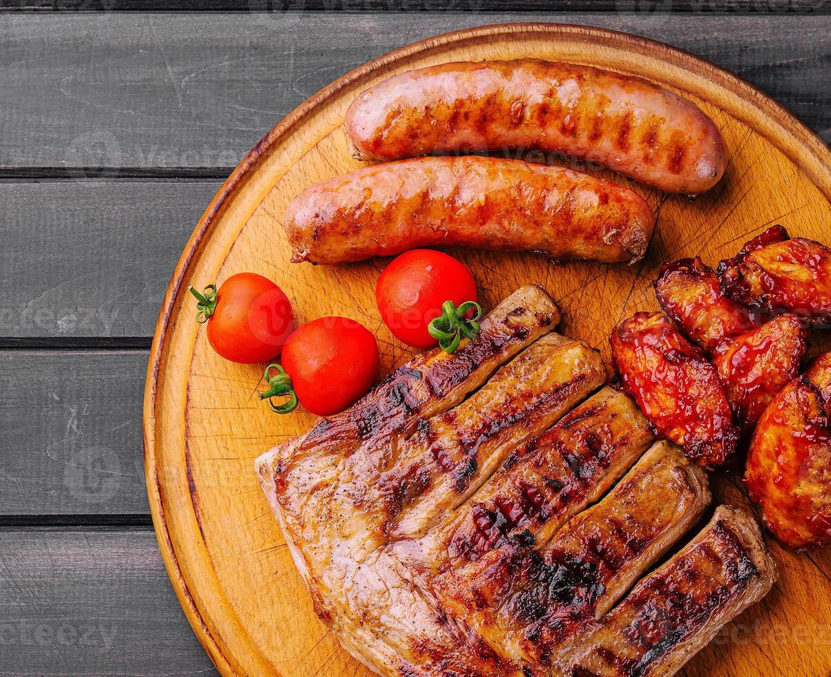 varkensvlees ribben met kip en worstjes Aan houten bord foto