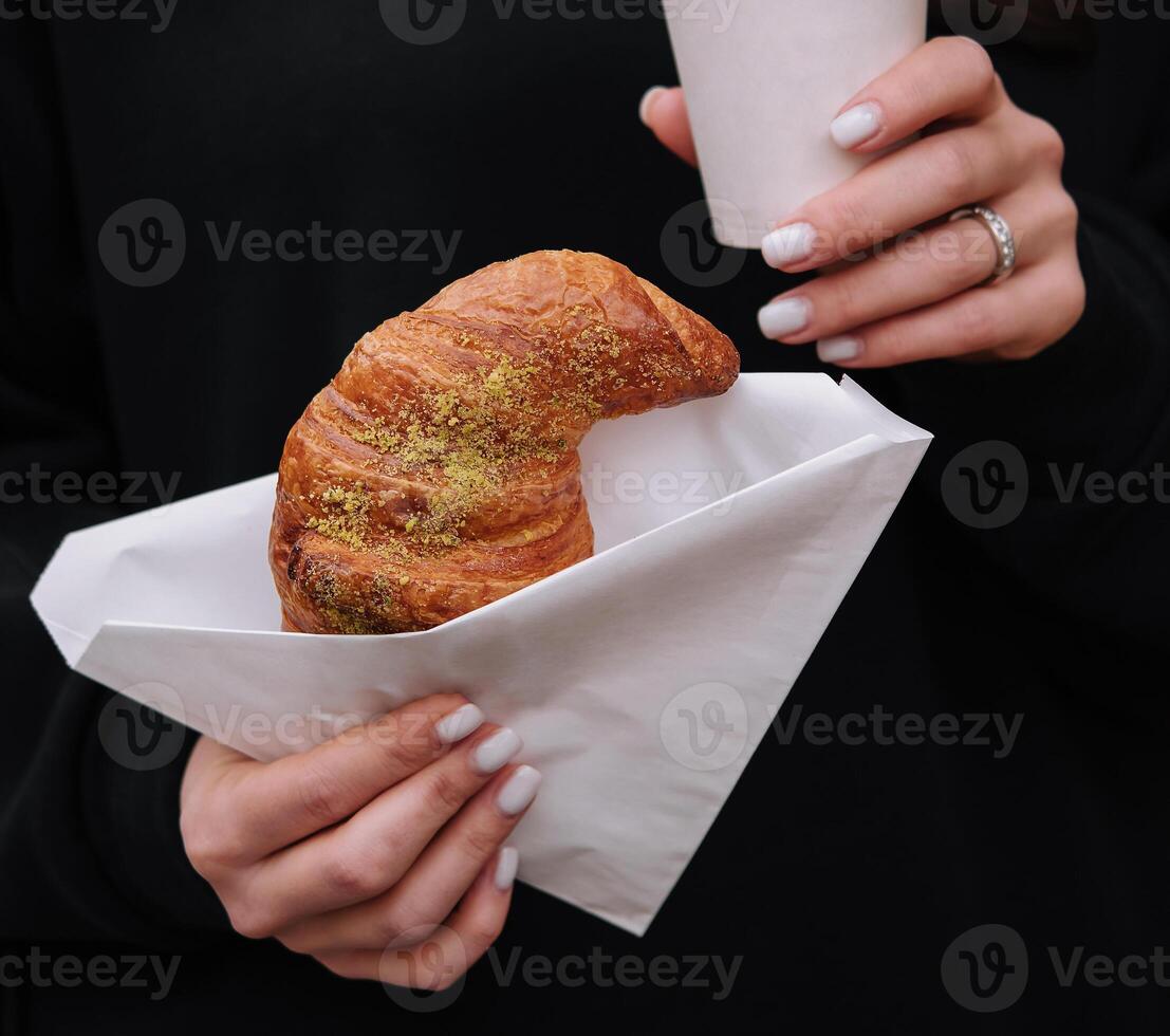 meisje aan het eten croissant met pistache poeder en drinken koffie Aan terras foto